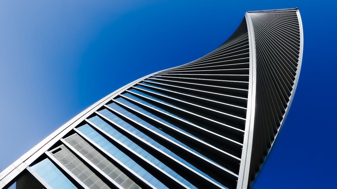 A modern, twisting skyscraper facade against a clear blue sky in Saudi Arabia.