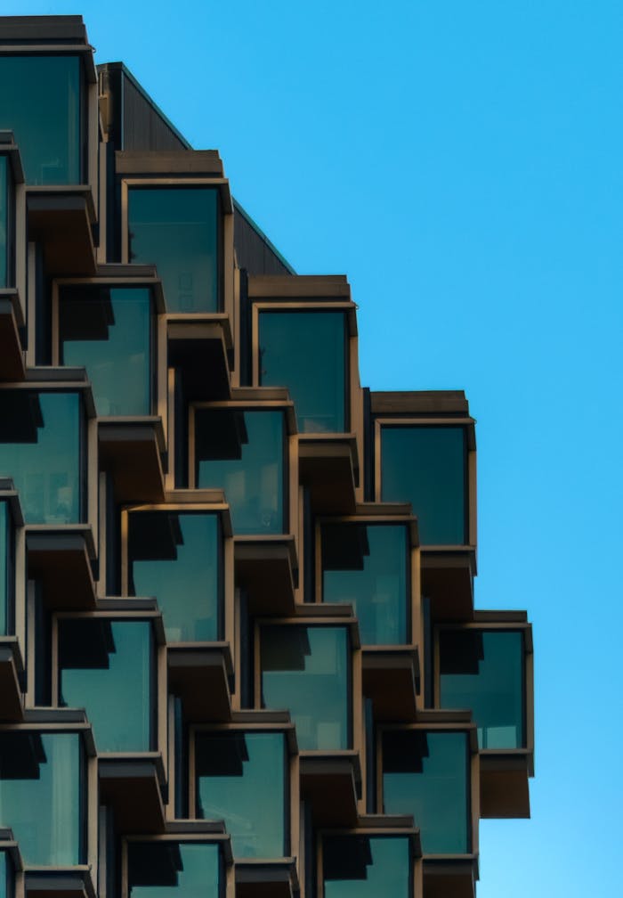 Modern architectural facade showcasing geometric design elements with a clear blue sky backdrop.